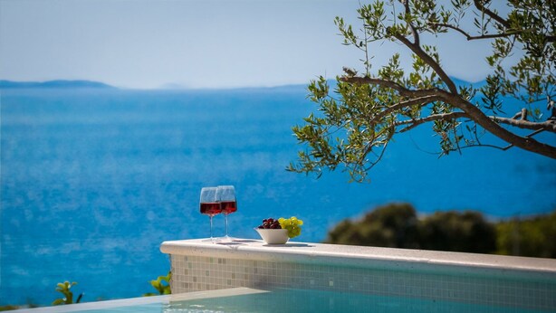 Ein Pool ohne Rand mit freiem Blick auf das Meer und die Berge.