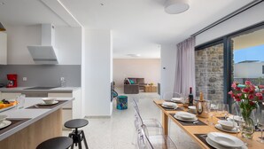A modern kitchen with a dining area, a sofa, and a view of the outdoors.