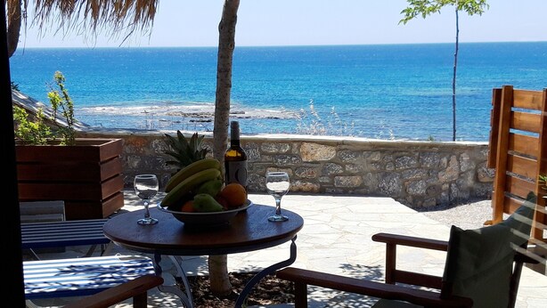 Ein Tisch mit Obstschale, Weinglas und Flasche, mit Blick auf das Meer.