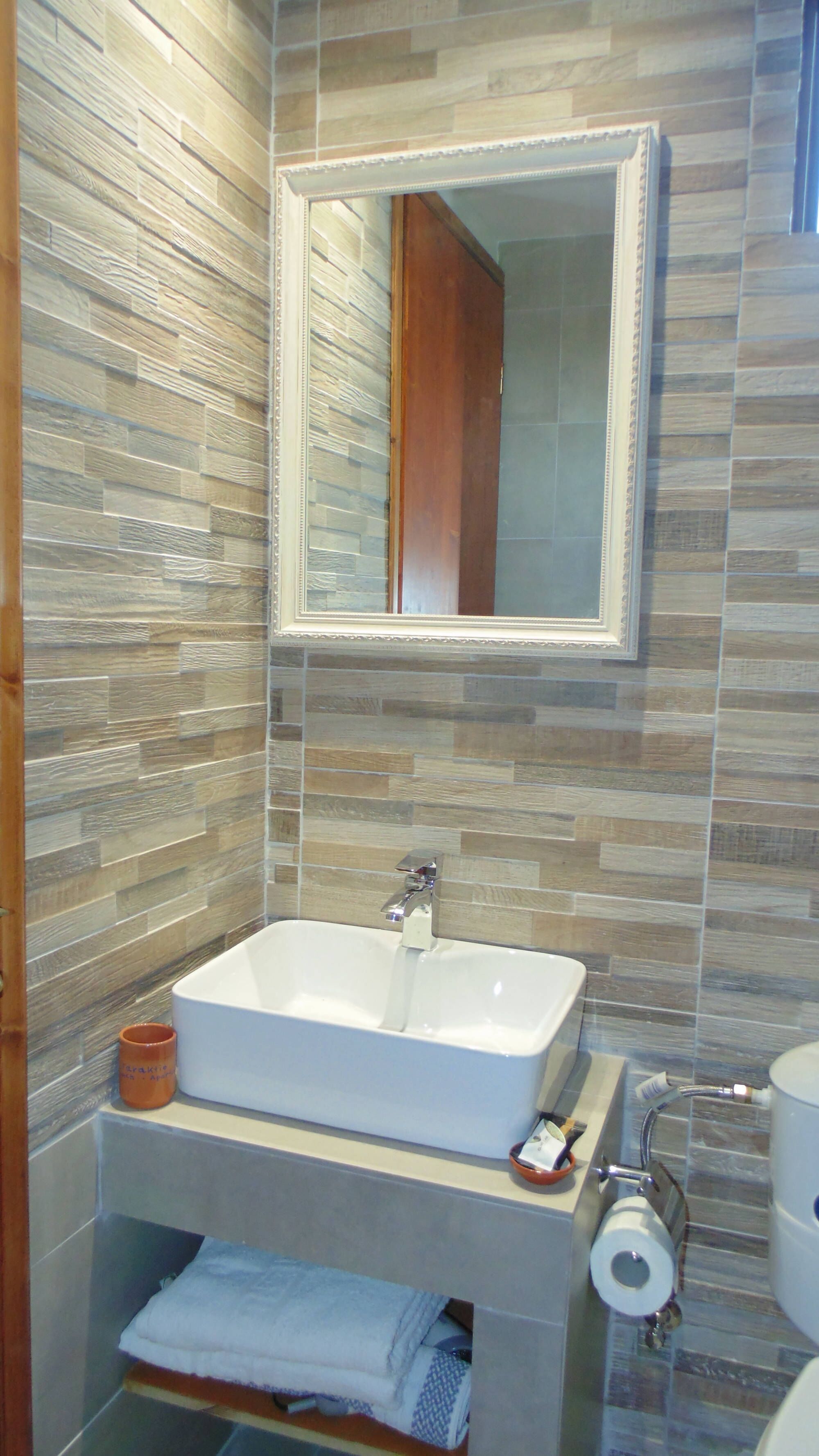 A bathroom with a rectangular sink, a mirror, and a towel rack.