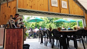 Um café ao ar livre com paredes, mesas e cadeiras de madeira, e dois sinais na parede.