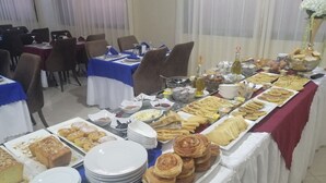 A buffet setup with various food items and a table with chairs. - Hotel Oasis Palace (Lkheng)
