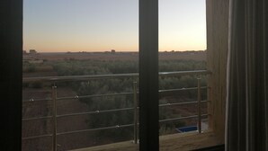 A balcony with a view of a rural landscape during sunset. - Hotel Oasis Palace (Lkheng)