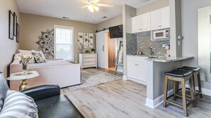 A modern kitchen with white cabinets, a black countertop, and a microwave. - Pretty Peony Steps to Pool - Myrtle Beach, SC (Myrtle Beach)