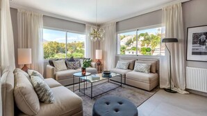 A modern living room with two sofas, a coffee table, and a view of greenery outside. - Villa Alva | Luxe Heated Pool Cinema Sunset Views (Marbella)