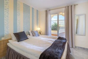 Hotellihuone, jossa on suuri sänky, yöpöytä, lamppu ja näkymä ulos.