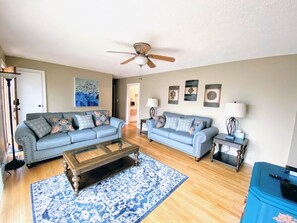 A living room with two sofas, a coffee table, and a ceiling fan.