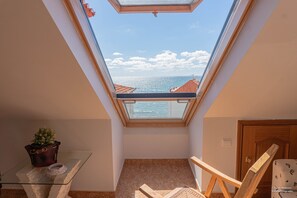 Une petite pièce avec un puits de lumière, une table en verre sur laquelle est posée une plante en pot et une chaise en bois.