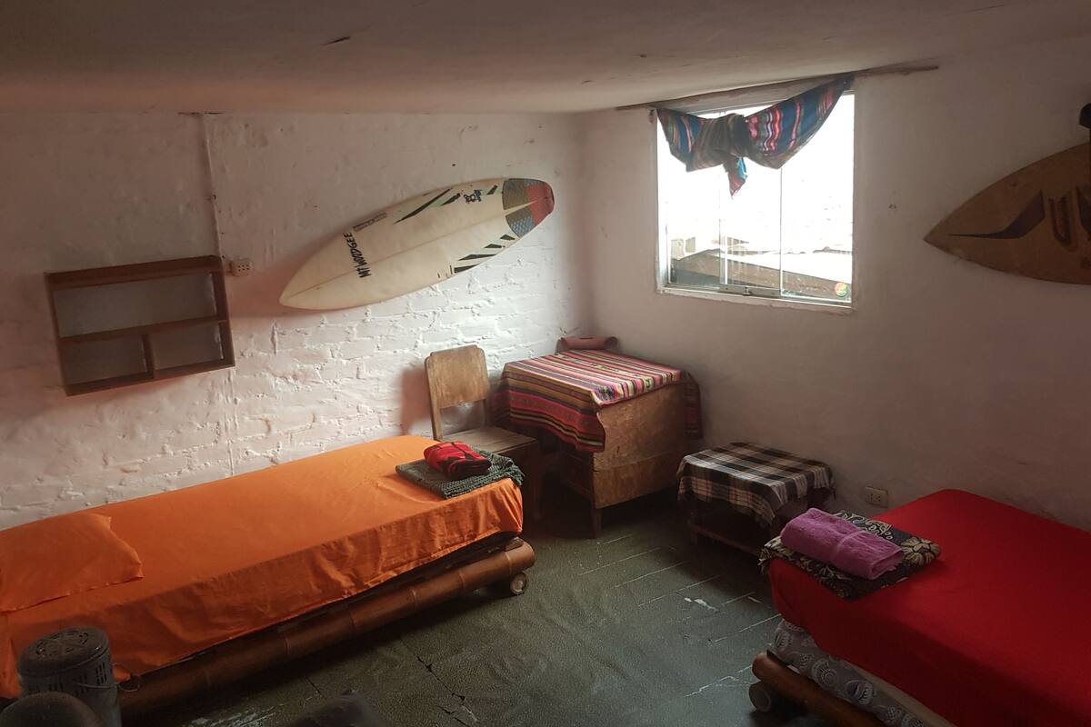 Una habitación pequeña y funcional con una cama individual, una mesita y una ventana.