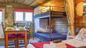 A bunk bed room with a wooden ceiling, a dining table with yellow plates, and a red blanket on the bed. - 1 bedroom accommodation in Brocklebank, near Caldbeck and Uldale (Brocklebank, near Caldbeck and Uldale)