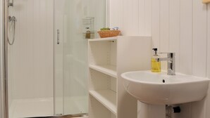A bathroom with a glass-enclosed shower, a white sink, and a mirror. - 1 bedroom accommodation in Brocklebank, near Caldbeck and Uldale (Brocklebank, near Caldbeck and Uldale)