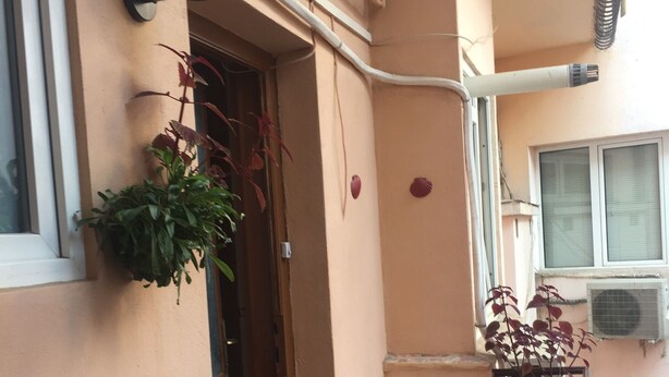 Un piccolo balcone privato con un tavolo e sedie, una pianta in vaso e un punto luce a parete.