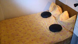 Un letto singolo con una coperta gialla e due cuscini neri.