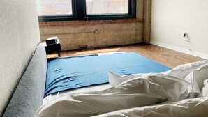 Una stanza con un letto, una finestra e un muro in mattoni.