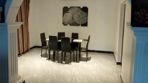 Een eetruimte met een tafel, stoelen, een plafondventilator en een kunstwerk aan de muur.