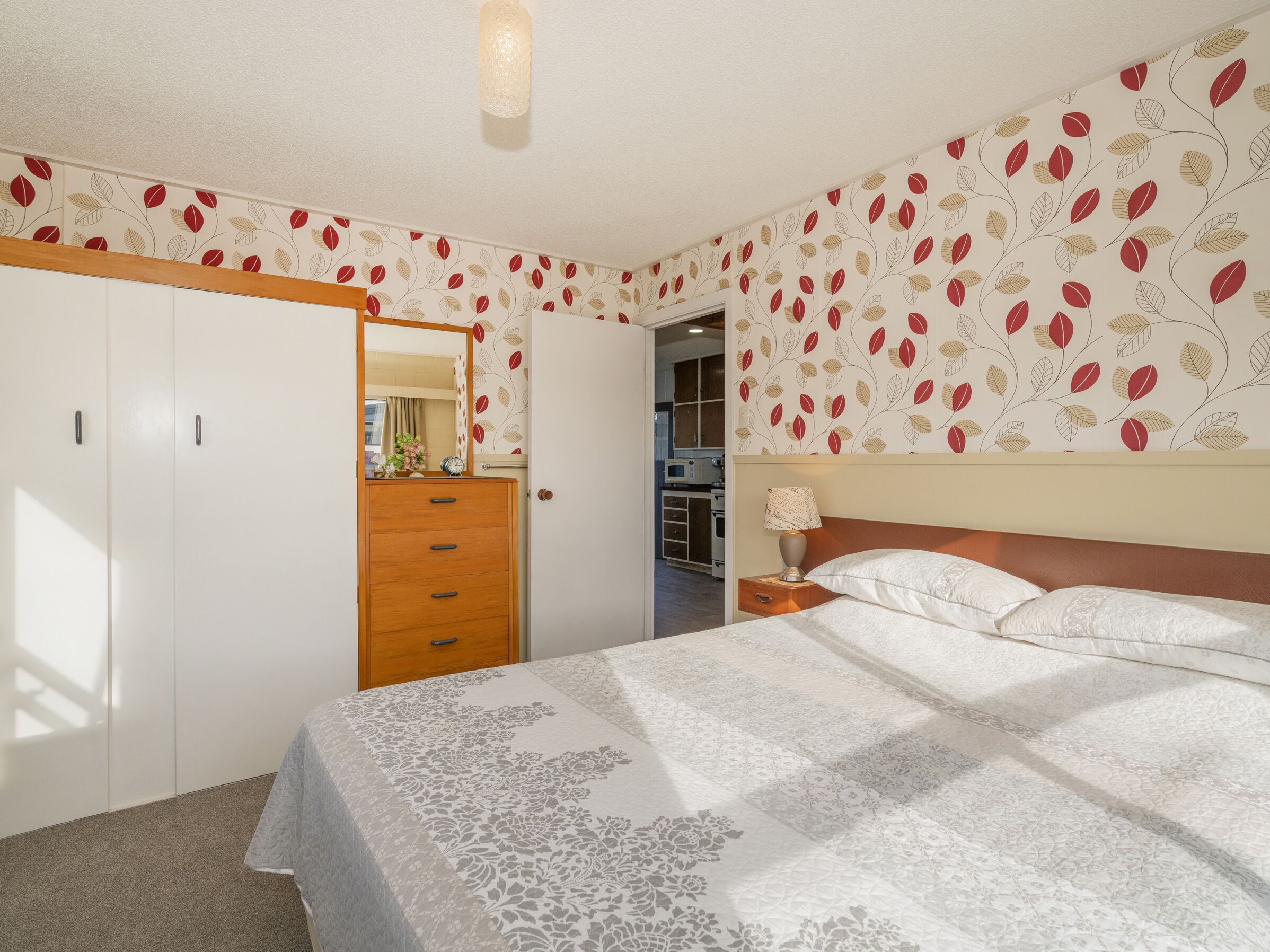 Un dormitorio con cama, cómoda, espejo y armario.