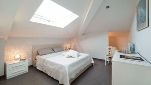 A bedroom with a skylight, a bed with a white bedspread, a bedside table with a lamp, and a chair with a tray of glasses. - Villa for 10 People with private pool, garden and free WiFi (Randazzo)