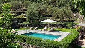 A swimming pool with lounge chairs and an umbrella, surrounded by stone walls and greenery. - Villa for 10 People with private pool, garden and free WiFi (Randazzo)