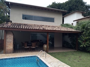 Une maison moderne dotée d’une piscine, d’un patio et d’un espace extérieur aménagé et couvert.