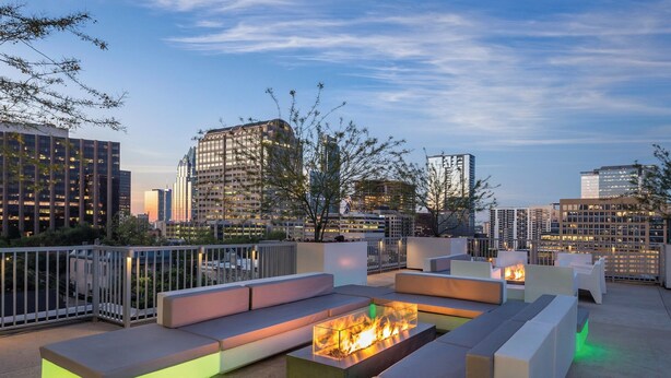 A rooftop lounge with modern seating and a central fire feature, overlooking a cityscape. - Prime Austin 2 BR downtown new location (Austin)