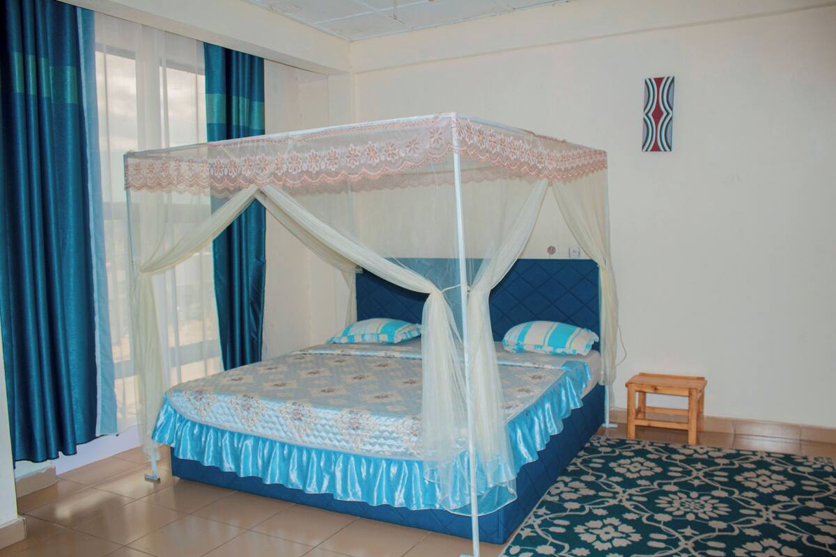 Un dormitorio con una cama, una mesita de noche, una ventana con cortinas y una decoración en la pared.