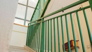 Una escalera con barandales verdes y una lámpara fijada a la pared.