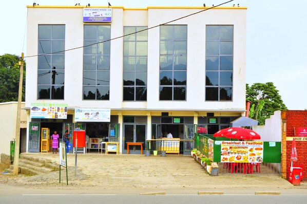 Two-story building with a storefront, outdoor seating area, and large windows.