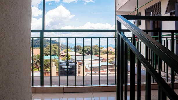Un balcón con barandilla metálica, vistas a una zona residencial y cielo despejado.