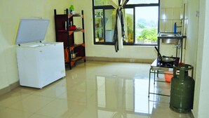 Una cocina con refrigerador, estufa a gas y una ventana con cortinas.