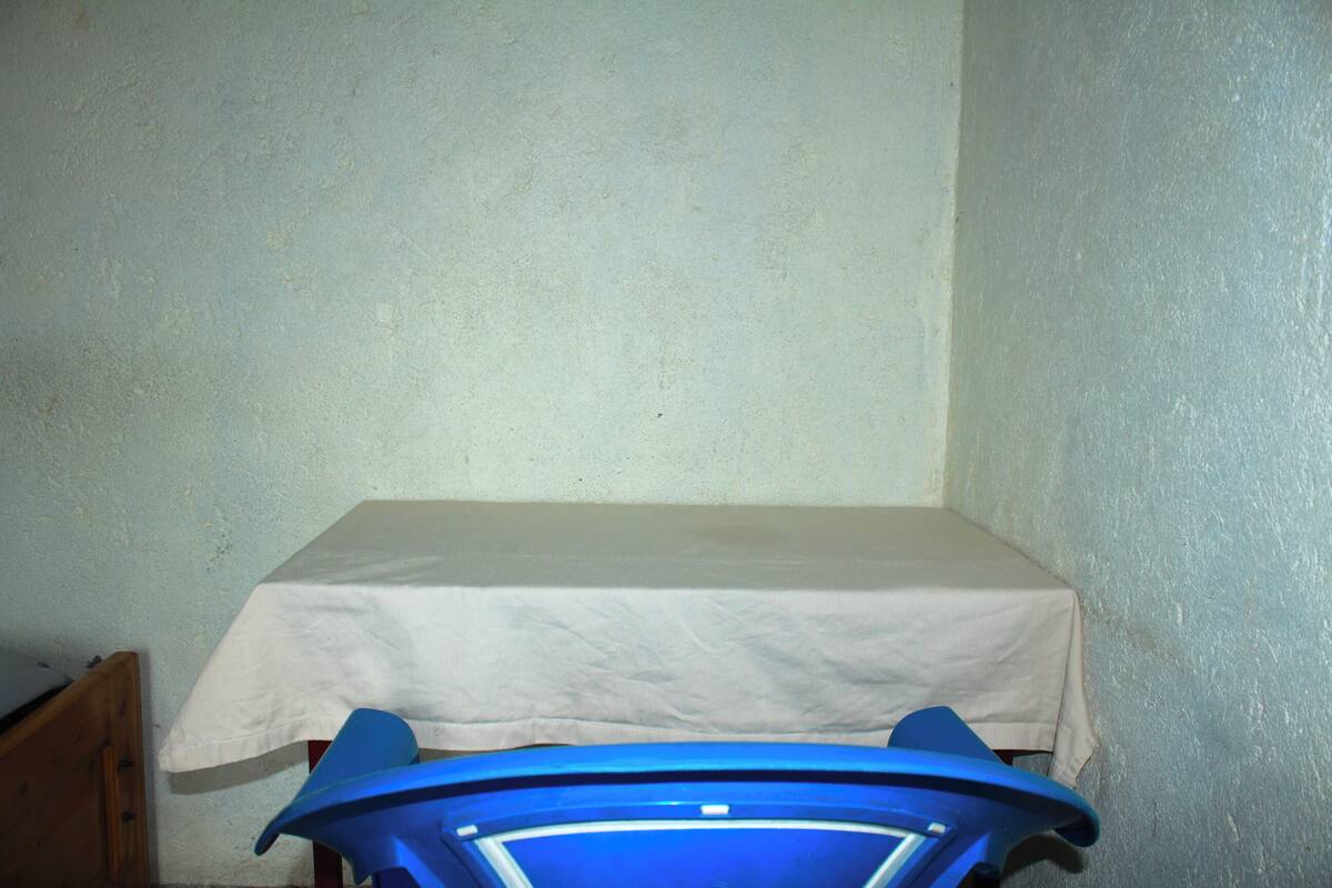 Una habitación pequeña con una mesa blanca y un objeto azul en una esquina.