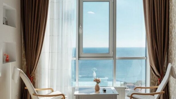 A room with a large window, two chairs, a small table, and a view of the sea. - Apartments Arcadia. Panorama of the sea. 3 bedrooms  (Odessa)