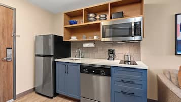 Una cocina compacta con refrigerador de acero inoxidable, microondas, cafetera y lavavajillas.