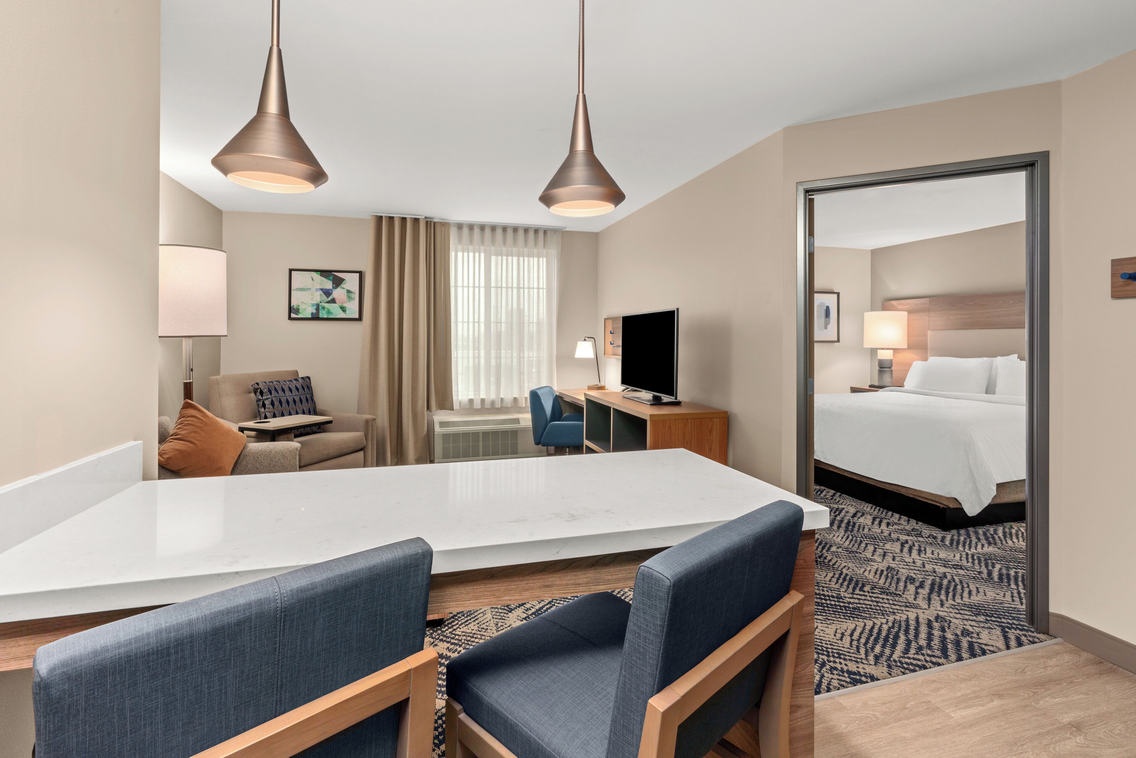 Una habitación de hotel con una cama grande, un escritorio, una silla, un televisor y una mesa de comedor.