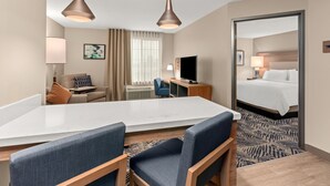 Habitació d'hotel amb un llit gran, un escriptori amb ordinador, una cadira, un sofà i dues làmpades penjants.