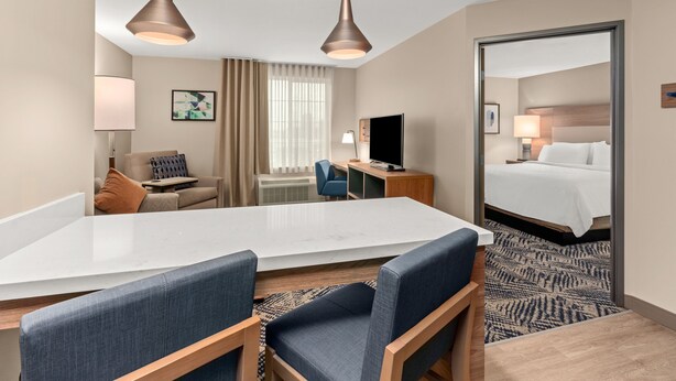 A hotel room with a large bed, a desk with a computer, a chair, a sofa, and two pendant lights. - Candlewood Suites Sumner by IHG (Sumner)