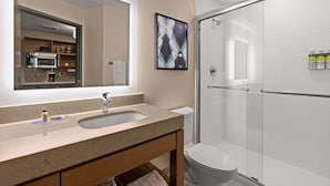 Un bany modern amb un mirall gran, un lavabo i una dutxa amb envàs de vidre.