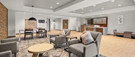A spacious lobby with a reception desk, seating area, and a patterned rug.