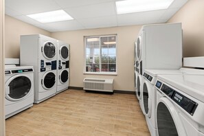 A laundry facility with multiple washing machines, a window with a view, and a tiled floor. - Candlewood Suites Sumner - Puyallup Area by IHG (Sumner)