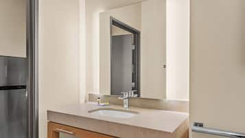 A bathroom with a sink, mirror, and wooden cabinet.