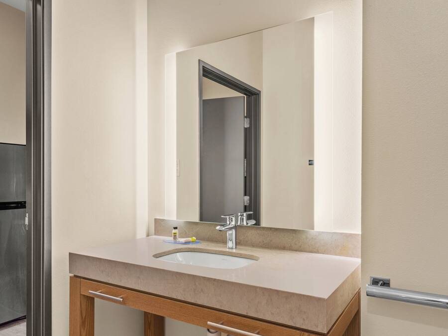 A bathroom with a sink, mirror, and wooden cabinet.