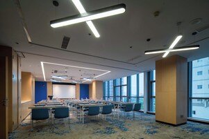Un salón de conferencias con mesas, sillas y una pantalla grande.
