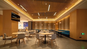 A modern restaurant interior with wooden panel ceilings, multiple dining tables and chairs, and a blue accent wall. - Holiday Inn Express Huaibei City Center by IHG (Huaibei)