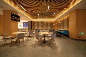 Un interior de restaurante moderno con techos de paneles de madera, varias mesas y sillas de comedor, y una pared de acento azul.