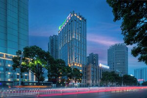 Un hotel moderno de gran altura con numerosas plantas, amplias ventanas y un cartel llamativo en la parte superior.