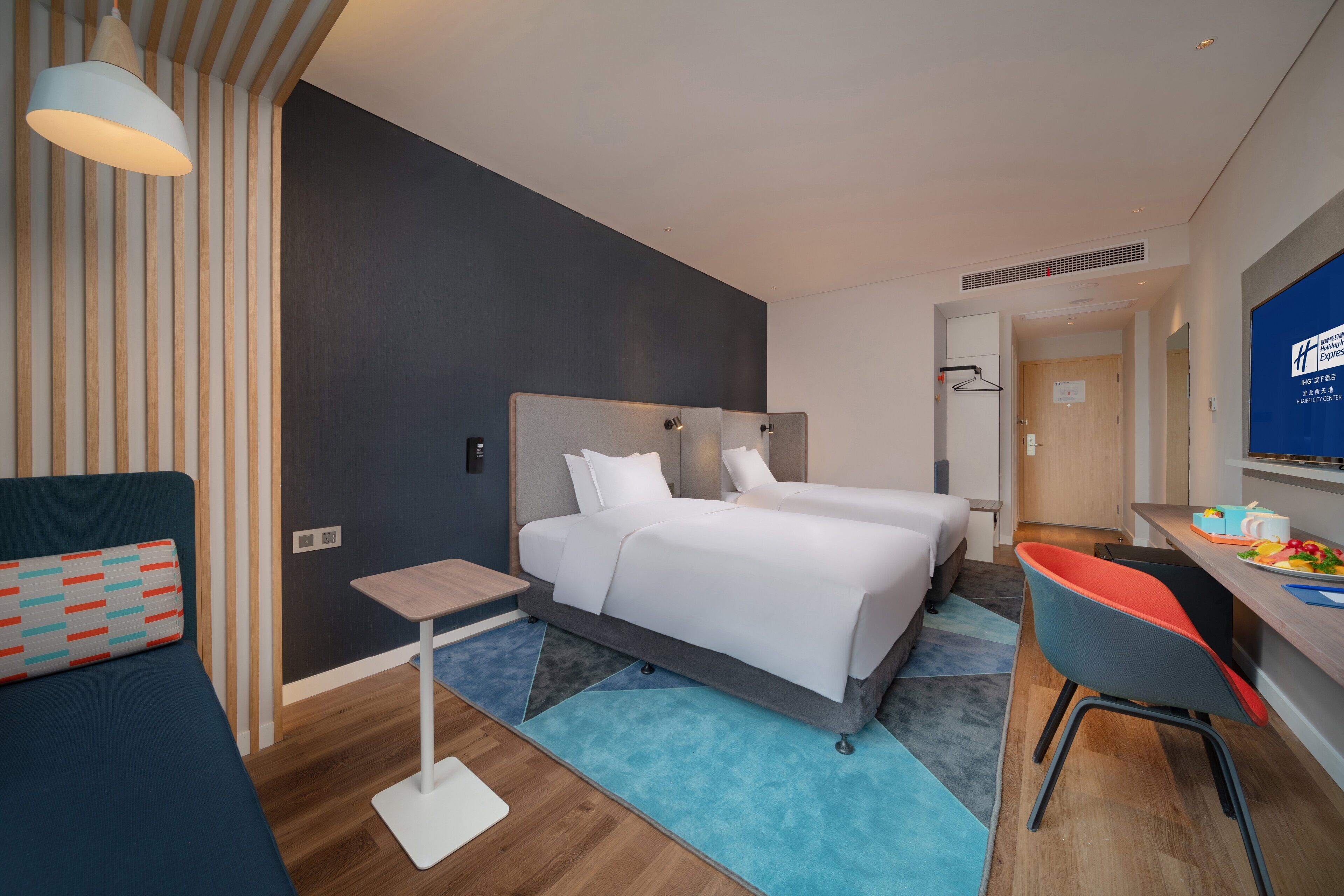 Une chambre d’hôtel moderne équipée de deux lits, d’un bureau, d’une chaise et d’une petite table.
