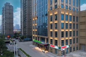 Un moderno edificio de hotel con fachada de vidrio, un letrero de Holiday Inn Express y una tienda 7-Eleven en la planta baja.