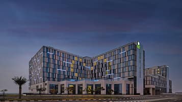 A modern hotel with a corner building design, featuring large windows and a prominent entrance.