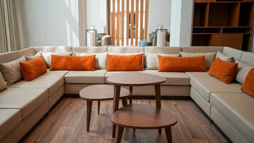 A modern living room with a sectional sofa, two round tables, and wooden flooring.