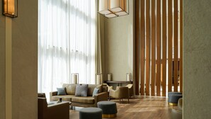 Un salón moderno con sofá, otomanas y un separador de madera.