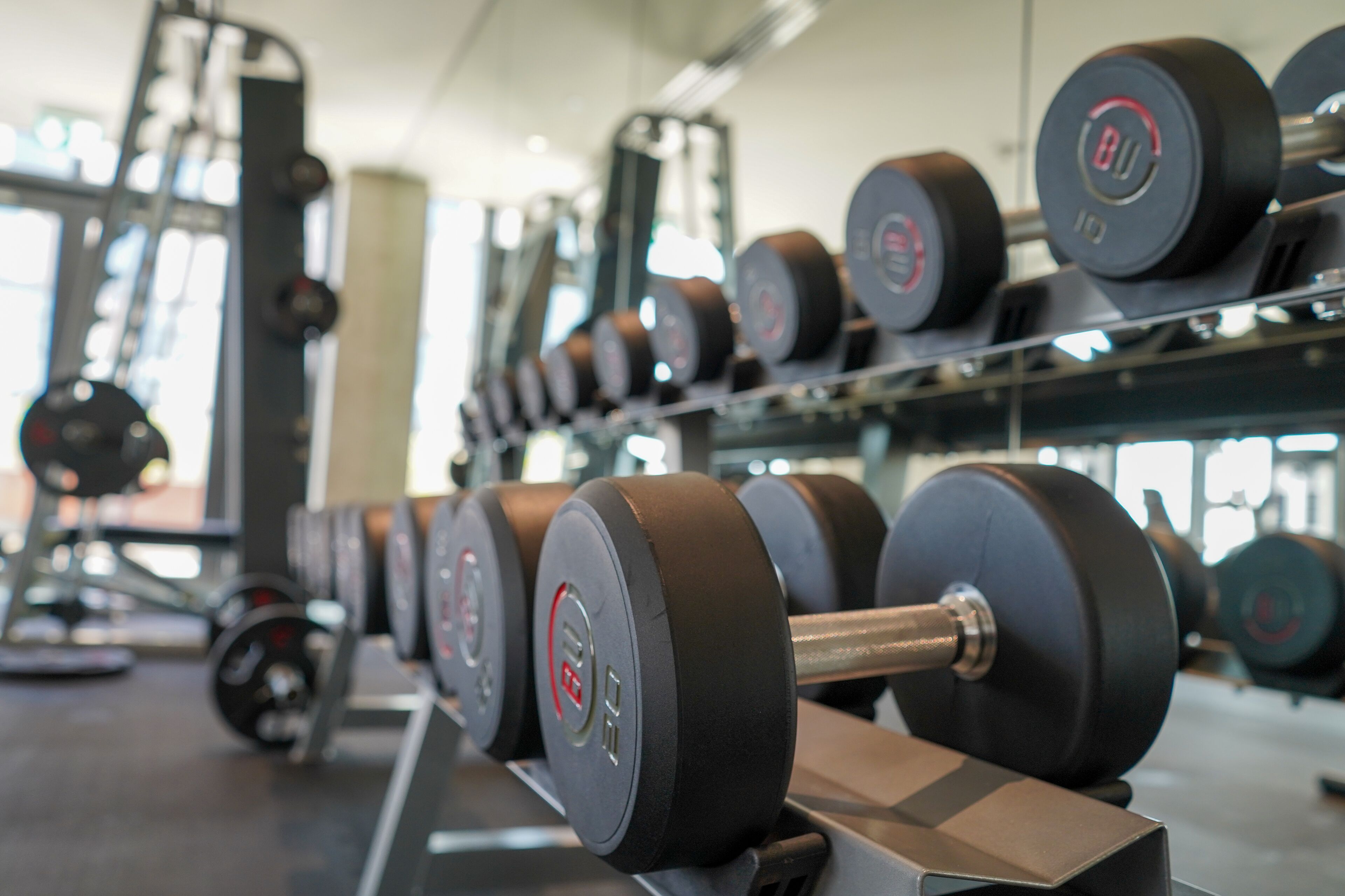 A gym with weightlifting equipment, including dumbbells and barbells.